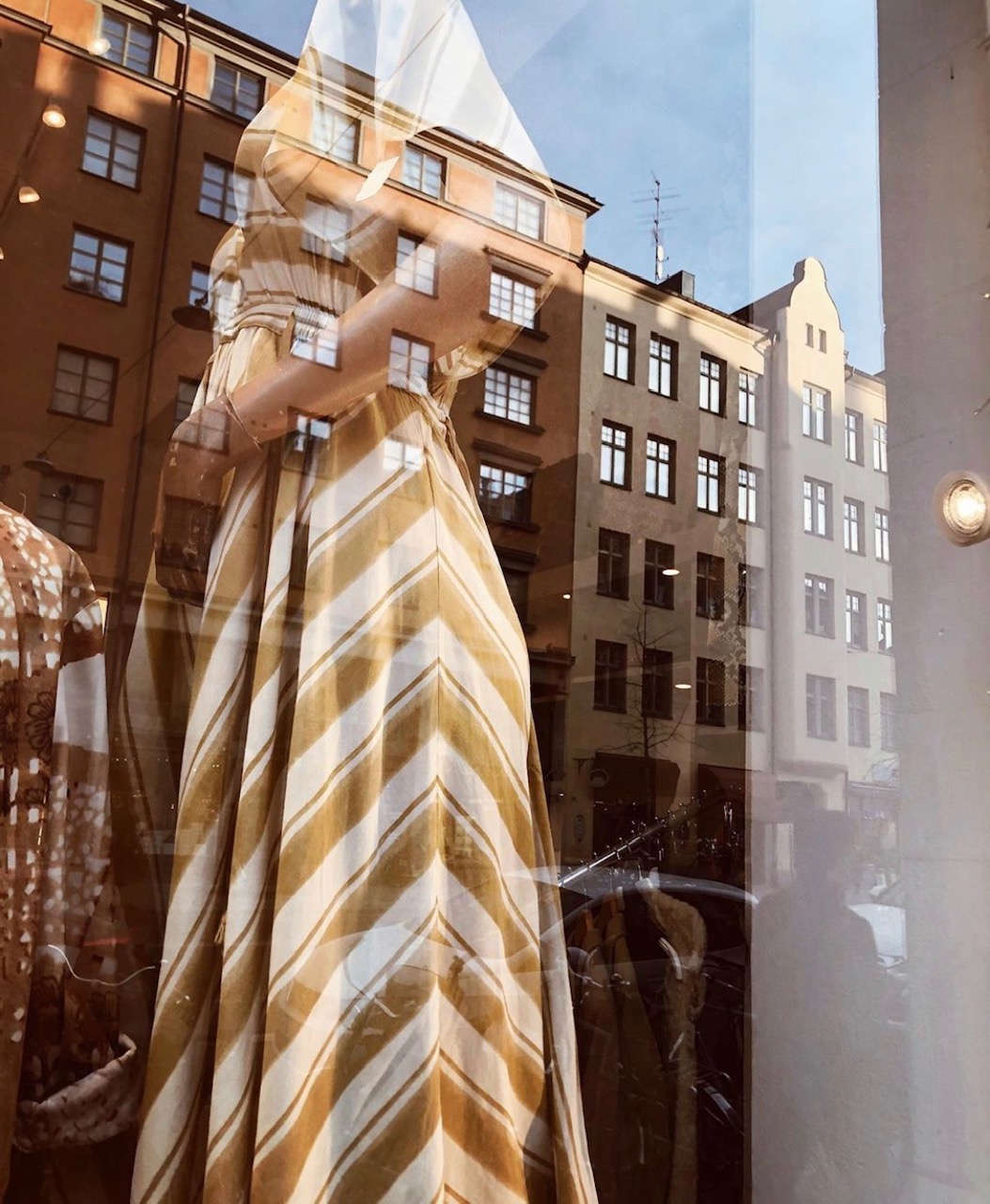 Bild på skyltfönster för en vintagebutik på södermalm med en vit och brun klänning